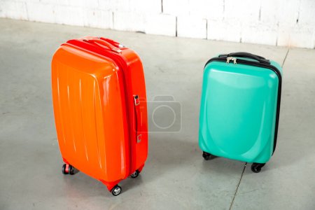 Foto de Bolsas de viaje naranjas y verdes sobre fondo de ladrillo blanco - Imagen libre de derechos