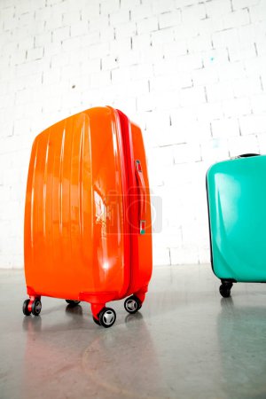 Téléchargez les photos : Sacs de voyage orange et vert sur fond de brique blanche - en image libre de droit