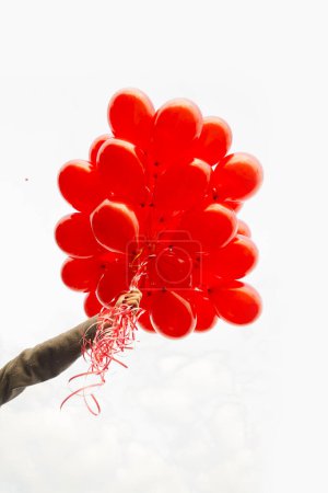 Téléchargez les photos : Fille main tenant des ballons rouges sur blanc - en image libre de droit