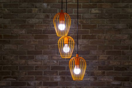 Foto de Primer plano de tres bombillas encendidas sobre fondo de pared de ladrillo marrón - Imagen libre de derechos