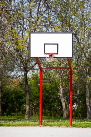 Photo for Red, empty outdoor basketball field with trees - Royalty Free Image
