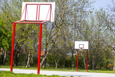 Photo for Red, empty outdoor basketball field with trees - Royalty Free Image
