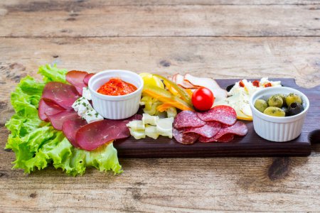 Téléchargez les photos : Assiette antipasto avec salami, olives et fromage sur fond de bois - en image libre de droit