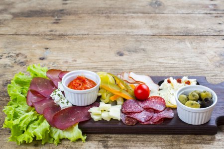 Photo for Antipasto catering platter with salami, olives and cheese on a wooden background - Royalty Free Image