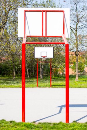 Téléchargez les photos : Terrain de basket-ball extérieur vide rouge avec arbres - en image libre de droit
