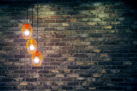 Foto de Primer plano de tres bombillas encendidas sobre fondo de pared de ladrillo marrón - Imagen libre de derechos
