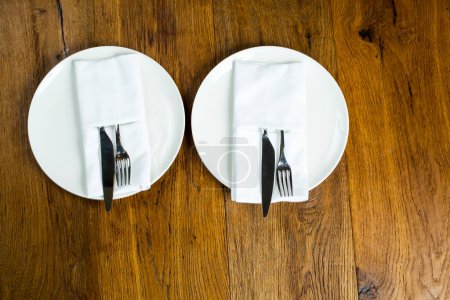 Téléchargez les photos : Assiettes vides avec couverts, fourchette et couteau sur serviette sur fond en bois. - en image libre de droit