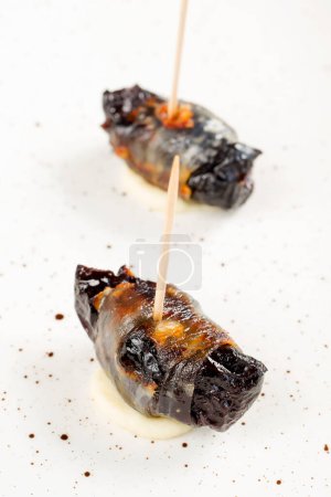 Téléchargez les photos : Pruneaux au four dans du bacon sur une assiette - en image libre de droit