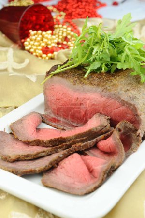 Téléchargez les photos : Steak de bœuf grillé rare tranché avec des feuilles de roquette - en image libre de droit
