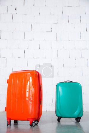 Téléchargez les photos : Sacs de voyage orange et vert isolés sur fond de brique blanche - en image libre de droit