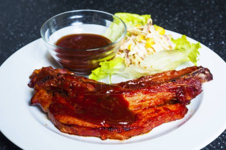 Téléchargez les photos : Porterhouse grillé tendre ou steak t-bone servi avec une salade d'herbes vertes fraîches accompagnée d'un barbecue ou d'une sauce tomate ketchup - en image libre de droit