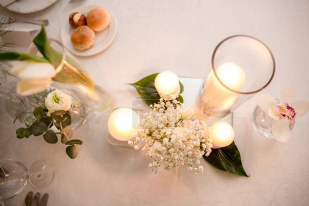 Foto de Juego de mesa blanco para fiesta con flores, velas y bombillas - Imagen libre de derechos
