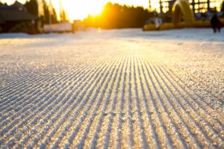 Foto de Primer plano de una pista de esquí recién preparada bajo el sol de la noche. Enfoque selectivo - Imagen libre de derechos