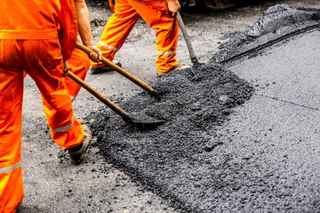 Photo for Workers hold shovel with fresh asphalt - Royalty Free Image
