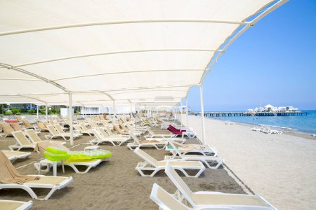 Photo for White plastic sunbeds in sandy beach under big parasol - Royalty Free Image