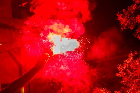 Photo for Football fans are holding torches in fire during a match - Royalty Free Image
