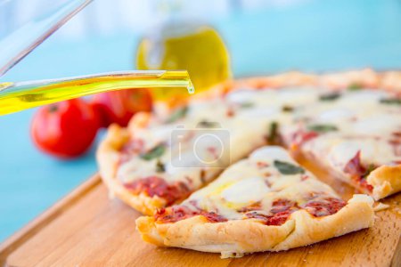 Foto de Pizza con aceite de oliva y tomates sobre fondo azul, Vista superior - Imagen libre de derechos