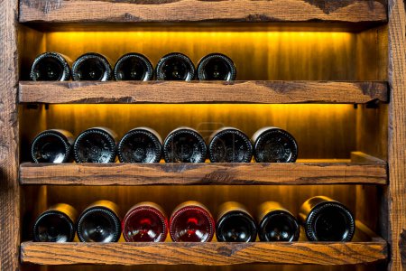 Photo for Wine bottles on wooden shelves - Royalty Free Image