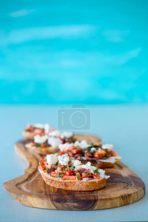 Téléchargez les photos : Brosse à la tomate, au fromage et à l'huile d'olive sur fond bleu - en image libre de droit