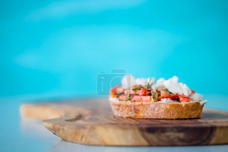 Foto de Bruschetta con tomate, queso y aceite de oliva sobre fondo azul - Imagen libre de derechos