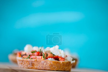 Foto de Bruschetta con tomate, queso y aceite de oliva sobre fondo azul - Imagen libre de derechos
