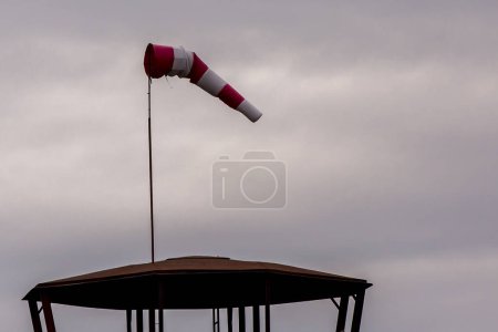 Photo for Red and white weather vane on a cloudy background - Royalty Free Image