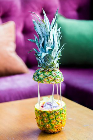 Foto de Cóctel tropical en piña sobre mesa - Imagen libre de derechos