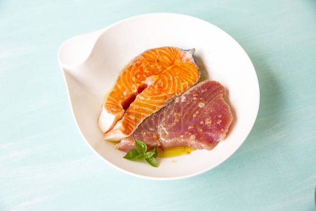 Téléchargez les photos : Saumon et thon marinés à l'huile d'olive sur fond bleu - en image libre de droit