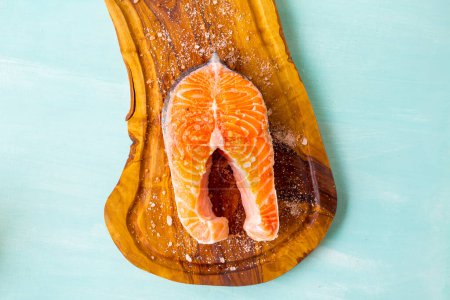 Téléchargez les photos : Poisson de saumon sur une planche de bois sur fond bleu - en image libre de droit