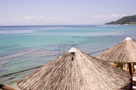 Téléchargez les photos : Parasols de paille de plage et soleil sur la plage - en image libre de droit