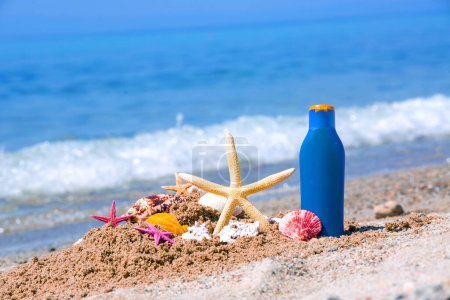 Téléchargez les photos : Crème solaire, coquillages et étoiles de mer sur la côte - en image libre de droit