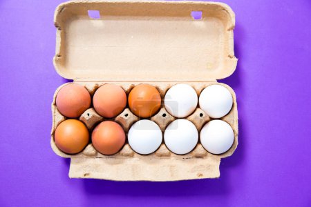 Photo for Fresh eggs in a cardboard on a purple background - Royalty Free Image