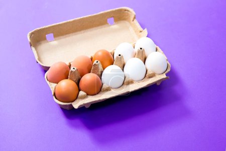 Foto de Huevos frescos en un cartón sobre un fondo morado - Imagen libre de derechos