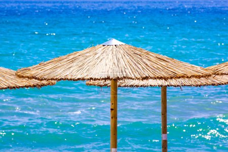 Foto de Tumbonas de playa y sombrillas de paja en la playa - Imagen libre de derechos