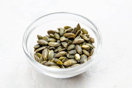 Photo for Pumpkin seeds in bowl on white background. - Royalty Free Image