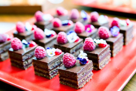 Photo for Small chocolate cakes with raspberries and edible flowers - Royalty Free Image