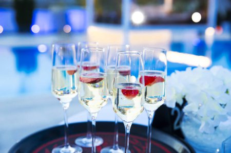 Photo for Champagne on a tray with strawberry next to the pool - Royalty Free Image