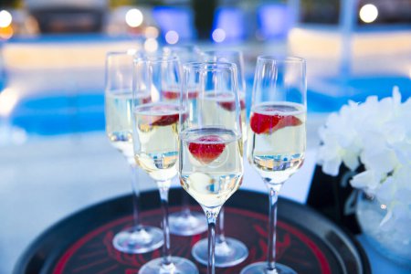 Photo for Champagne on a tray with strawberry next to the pool - Royalty Free Image