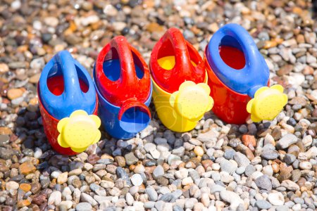 Téléchargez les photos : Arrosoirs colorés enfantins sur la plage - en image libre de droit