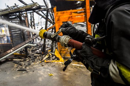 Téléchargez les photos : Pompier éteint le feu avec de l'eau - en image libre de droit