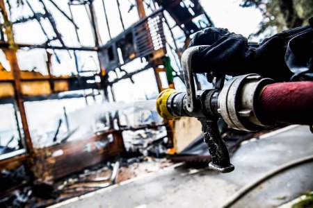 Téléchargez les photos : Pompier éteint le feu avec de l'eau - en image libre de droit