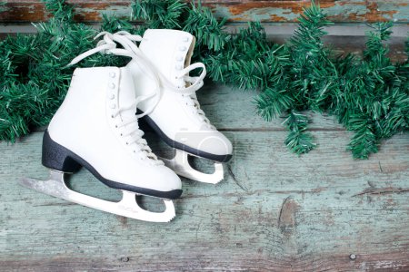 Foto de Patines de hielo vintage para patinaje artístico con rama de abeto sobre fondo rústico. Decoración de Navidad. - Imagen libre de derechos