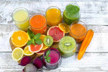 Téléchargez les photos : Jus de désintoxication frais de fruits et légumes dans des bouteilles en verre sur fond de bois - en image libre de droit