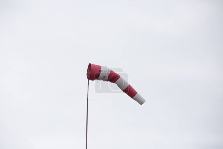 Foto de Veleta meteorológica roja y blanca sobre fondo nublado - Imagen libre de derechos