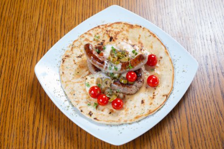 Photo for Grilled sausage in a tortilla with tomato and spices - Royalty Free Image