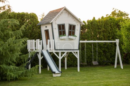 Photo for White wooden children's house with slide and swing - Royalty Free Image