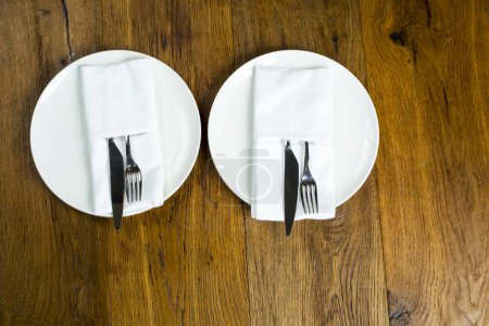 Téléchargez les photos : Assiettes vides avec couverts, fourchettes et couteaux sur serviette sur fond bois. - en image libre de droit