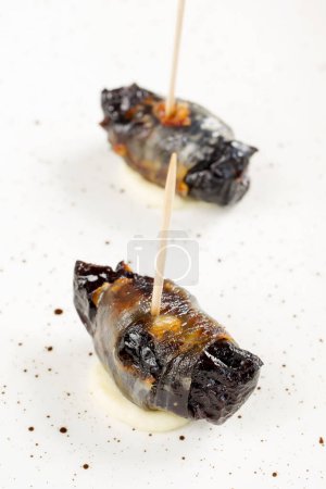 Photo for Baked prunes in bacon on a plate - Royalty Free Image