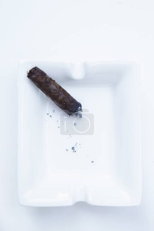 Téléchargez les photos : Cigare fumeur dans un cendrier isolé sur blanc - en image libre de droit