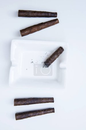 Téléchargez les photos : Cigare fumeur dans un cendrier isolé sur blanc - en image libre de droit